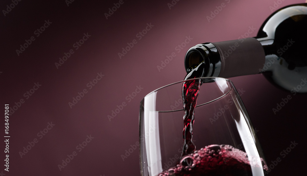Ein Weinglas und Rotwein wird hinein gegossen
